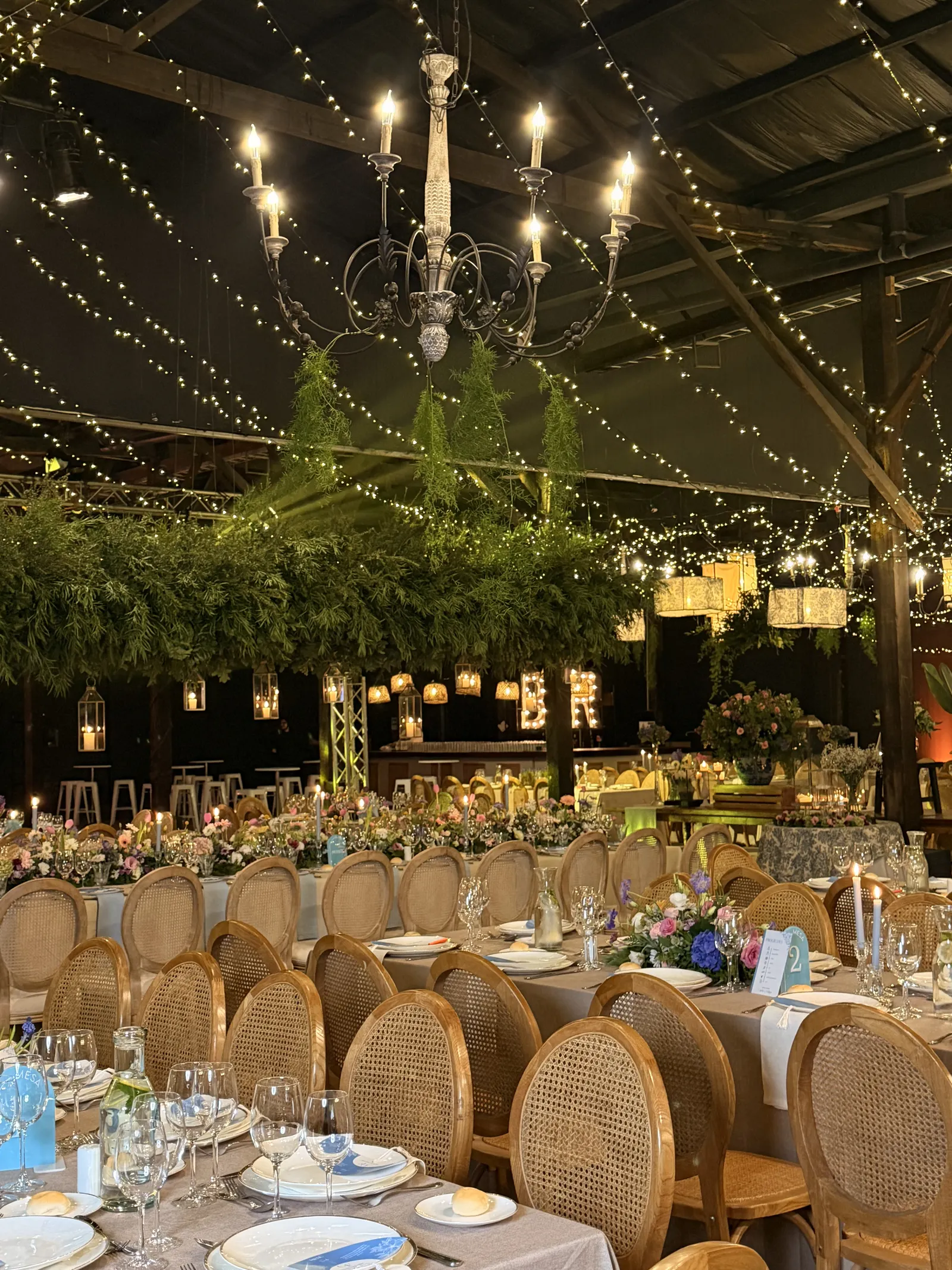 Salón preparado para cena con vegetación e iluminación
