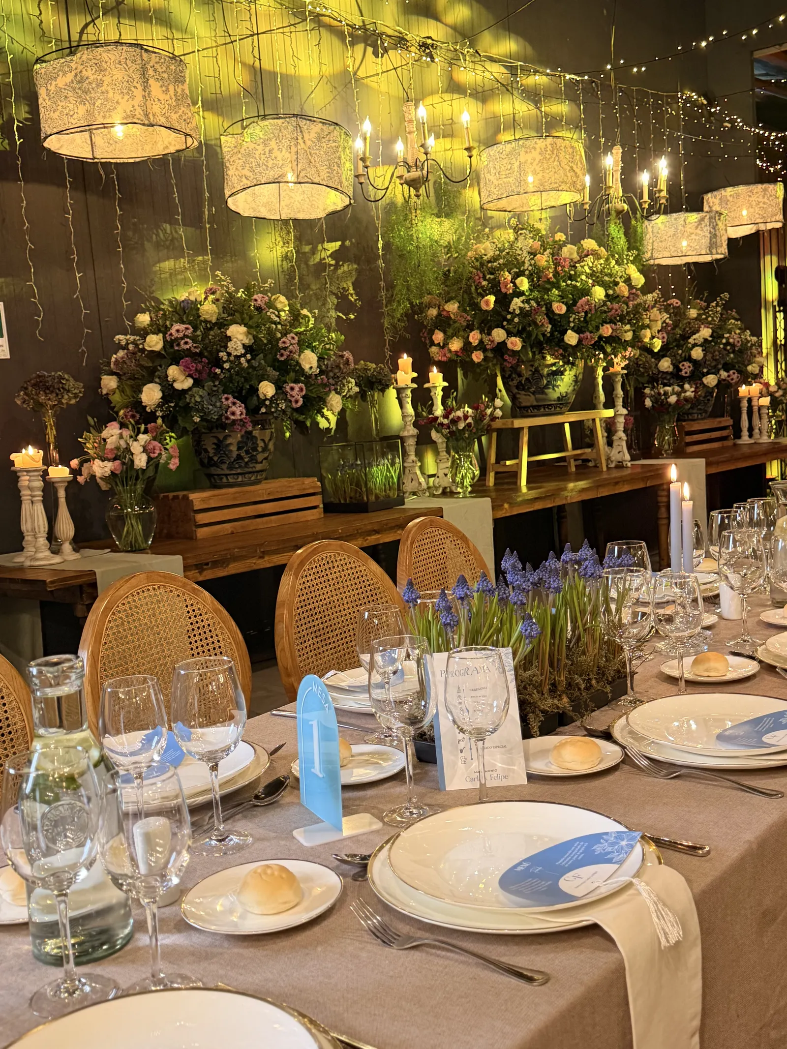 Mesa nocturna con flores y lámparas suspendidas